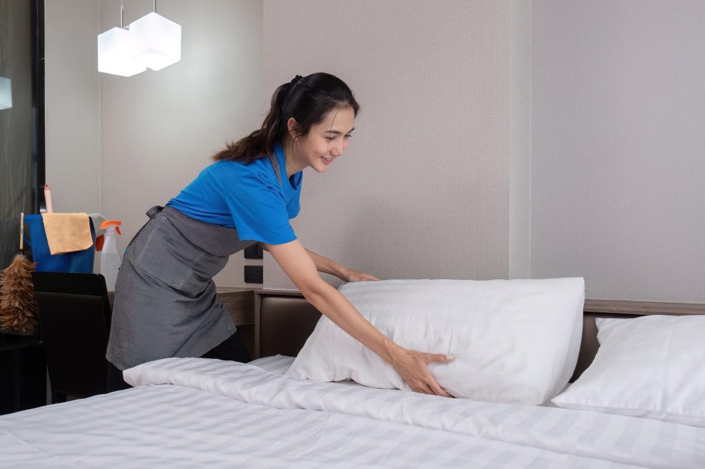 The bedroom maid is cleaning the bed and preparing the bedding.